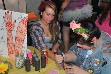 Junior Peyton Oller applies a henna tattoo to junior Maddie Leary.