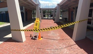 Caution tape and cones mark the spot where a pothole opened in front of the school cafeteria