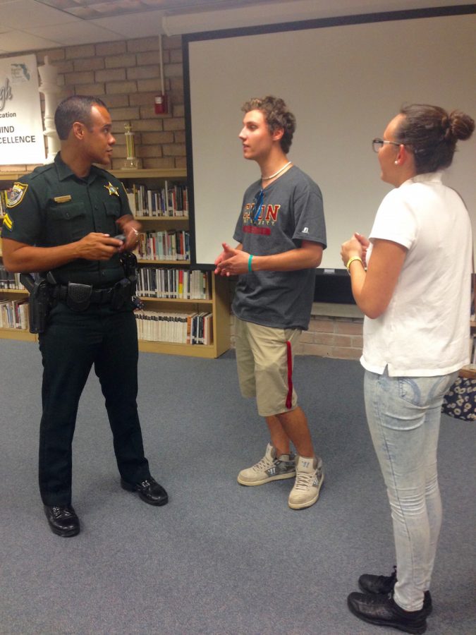 Asking Corporal John Martinez questions after his college safety presentation in the media center, seniors Katy Johnson and Austin Altevogt discuss the proper defensive stance taught in the police academy.