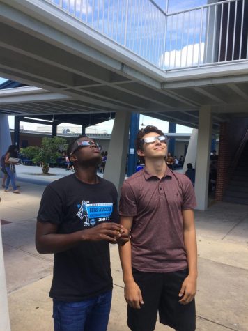 Senior Liam Wiles and junior Robbie Dujovne use their solar eclipse glasses to look at the sun. 