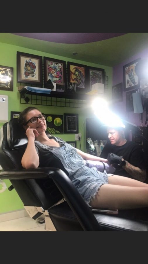 Aislinn O'Neill looks away  while getting her flower tattoo.
