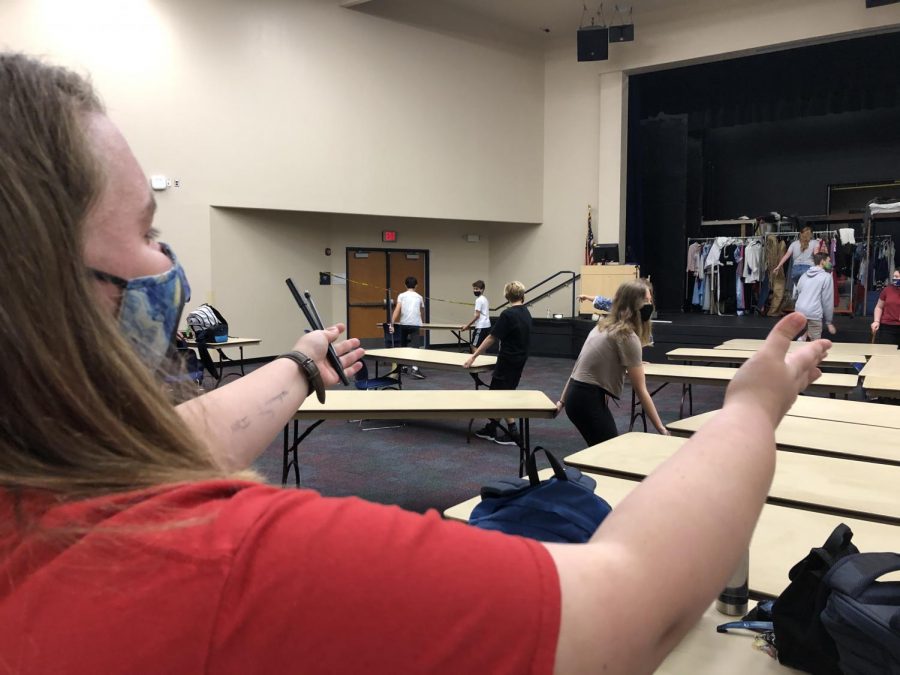 Haley Tucker (11) directs drama students to move tables in the auditorium in order to create a barrier between high school and middle school students. It helps them work more efficiently, said Tucker.