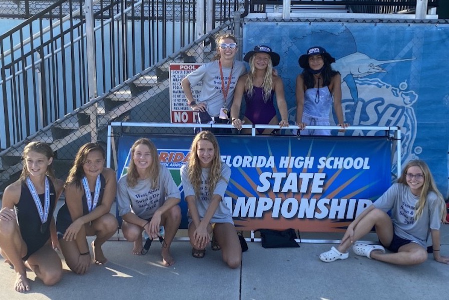 Eliza H. (8), Lillian Altman (10), Kalia Clary (11), Ava Auter (10) and Nicole R. (8) pose in front of the state championship banner with Allison Clark (11), Layla Auter (12), and Katelyn Owl (12) behind it. (Kyle Berry)