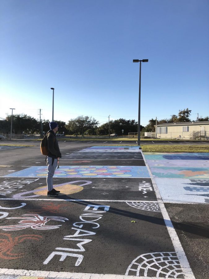 Senior+Evan+Ratkus+walks+around+the+auditorium+parking+lot+before+school+starts.