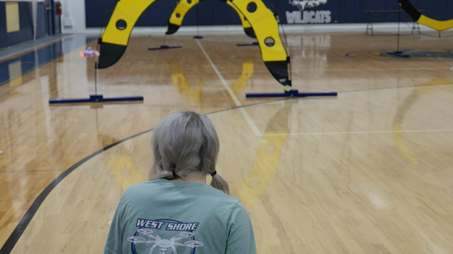Freshman Arabella Dias monitors the trajectory of her drone in as she guides it through an obstacle course in the gym on Feb. 19.