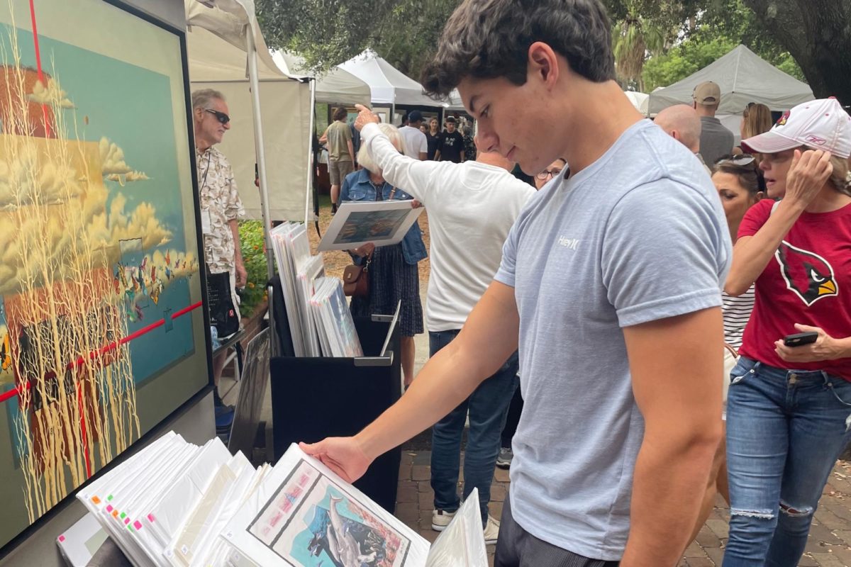 Senior Josh Fischer views a print of “Humpback Fantasy” by Rolly Ray Reel at the 50th Annual Autumn Art Festival in Winter Park on Oct. 8. “The venue was nice, and there were plenty of good choices in art whether you prefer abstract, surrealism, or pottery,” Fischer said.