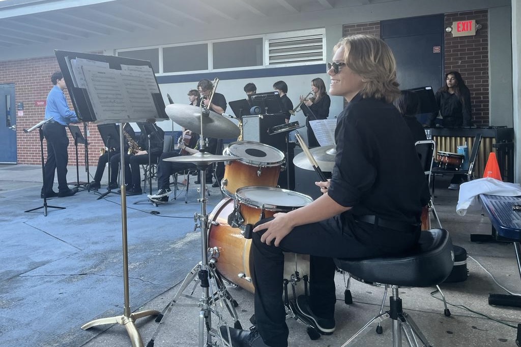 At Friday’s Noche de Encanto, hosted by the Spanish Honor Society, freshman and drummer Harper Millband smiles at the crowd before the jazz performance begins. “Just the joy that I get from people when they listen to us perform makes me happy,” he said.