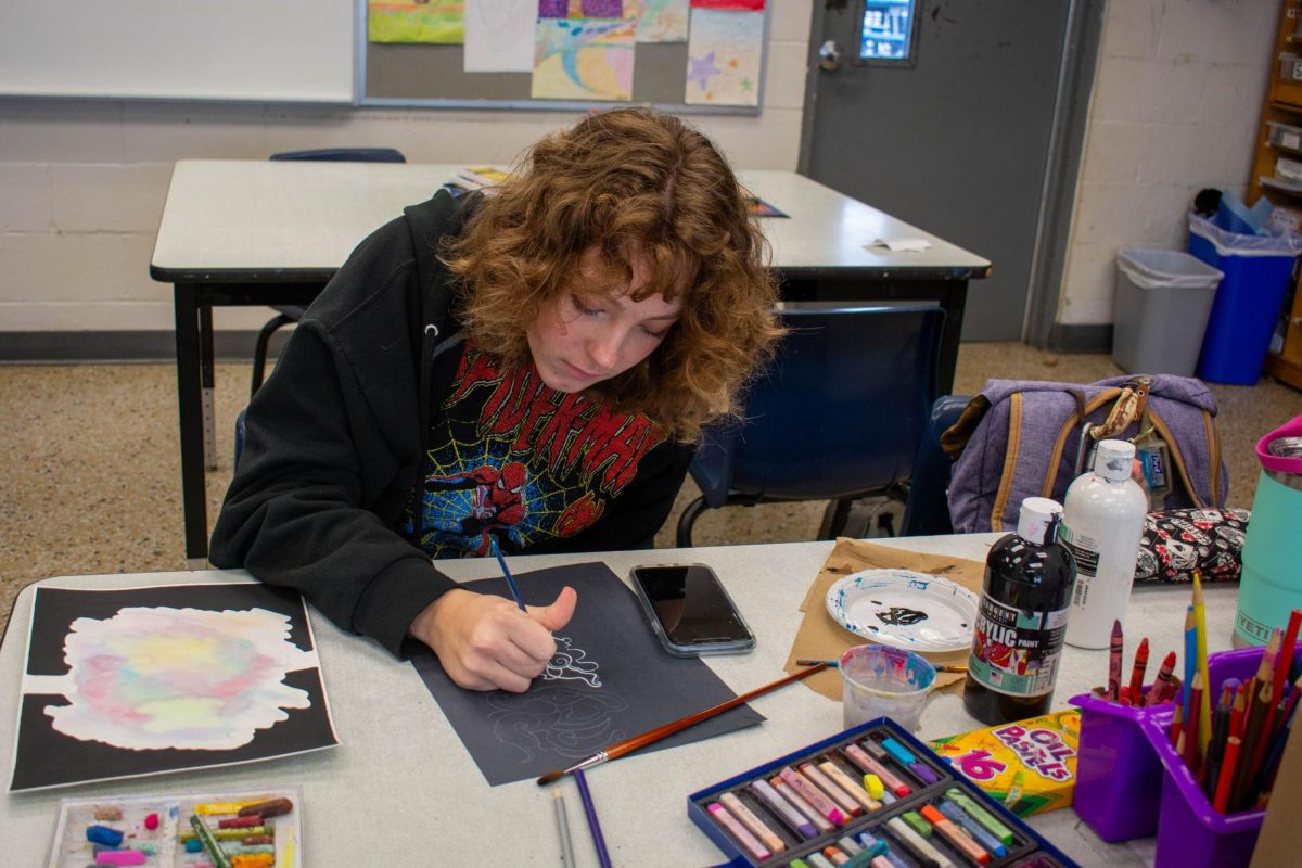 Junior Siera Crum uses white paint on black paper to depict a dreamlike art piece on Jan. 16. The idea is to draw without the presence of your conscience, Siera said, because dreams come from your subconscious.