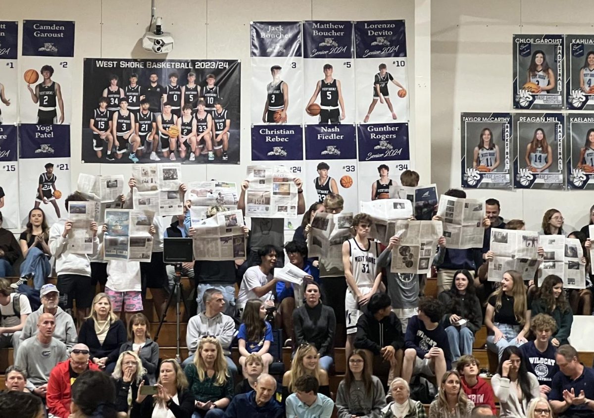 The Wildcats students' section reads the newspaper while the Space Coast Jr./Sr. High School varsity roster is called out before the boys basketball senior night game on Feb. 1. "I thought it was funny," teacher Austin Glezen said. "The scoreboard says [Space Coast] wasn't worth our time!"