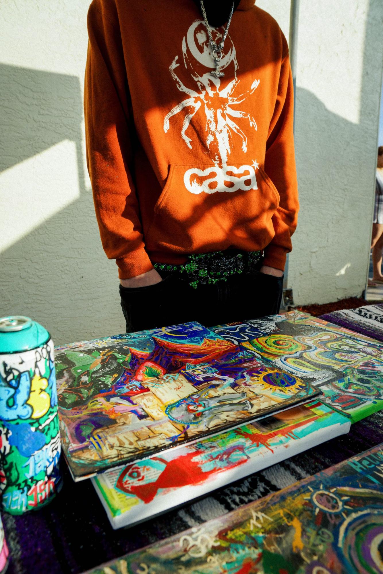 Displaying Casa Noche artwork, Vignier poses with a one-of-a-kind orange hoodie from his brand. 