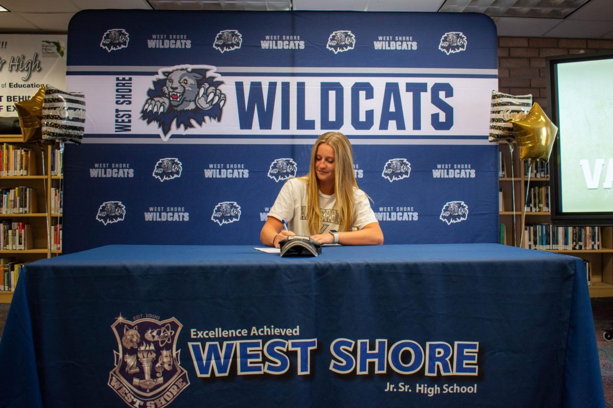 Girls lacrosse captain Kiera Runske (12) signs her contract to play womens lacrosse for Vanderbilt in the media center on on April 7. “I was so grateful to everyone who came out to support and all of the effort from admin, Kiera said. It was such a great little celebration!