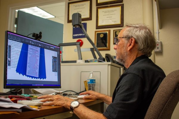 Journalism teacher Mark Schledorn edits a design from a students story from the latest issue of the Roar. Hes firm with a lot of stuff, but he does it in a way that maintains engagement and students self-worth,   Principal Rick Fleming said.