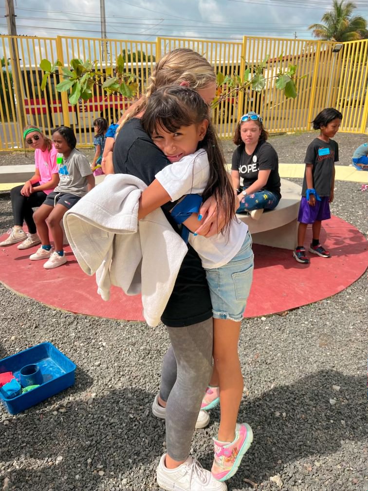 Having grown close over the week they spent together, senior Mykaela Brown and Camila, the young girl, hug.