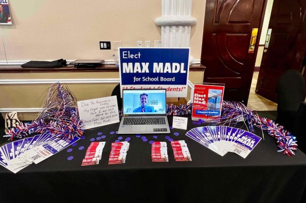 Max Madl appears at his school board campaign booth through a virtual call due to a flight cancellation in August 2024. 