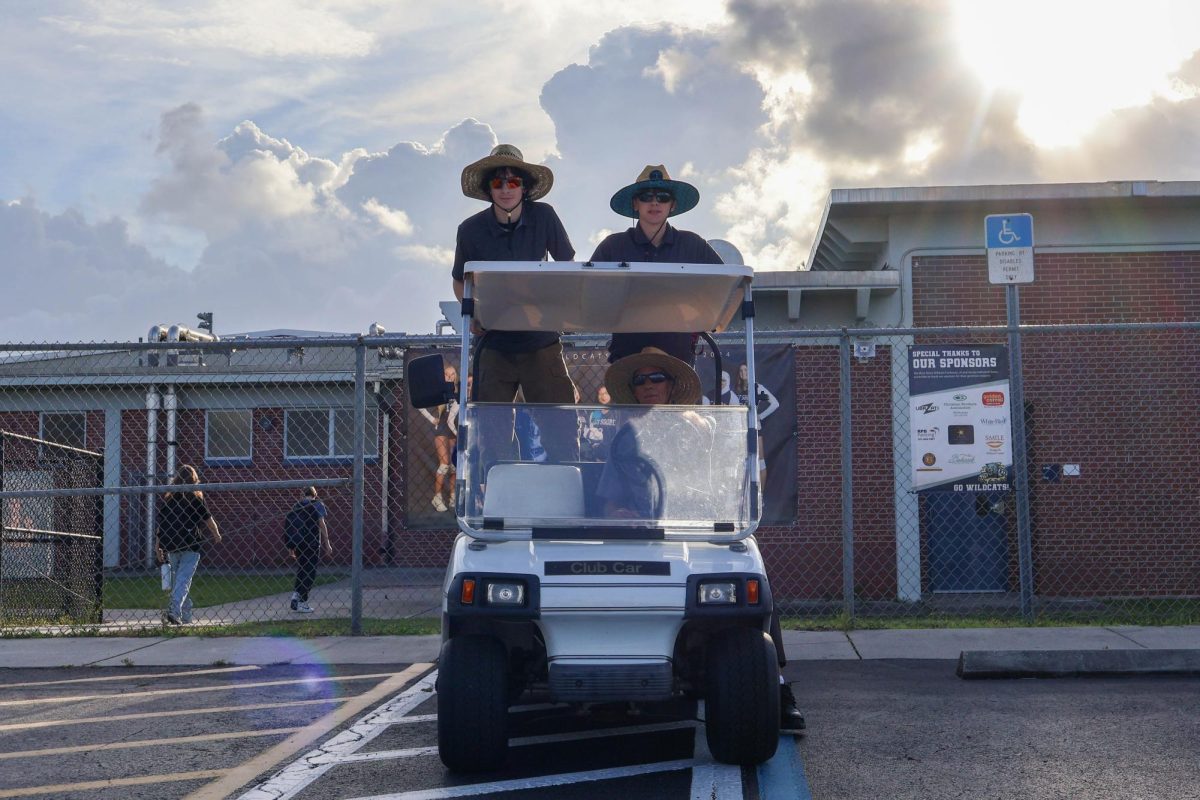 Seniors Aiden Dabbs and Nate Witteman ride on John Villano's golf cart, experiencing a day in the life of their hero on Sept. 25, 2024.