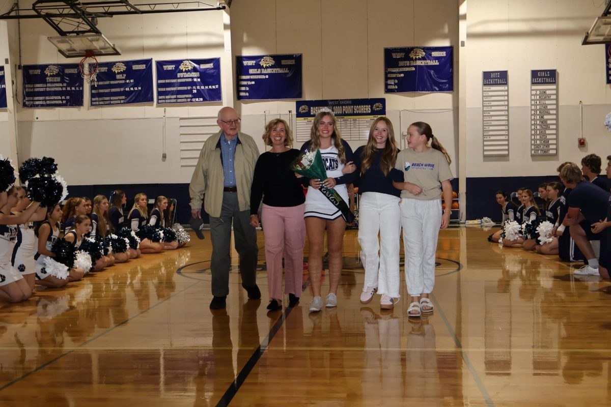 Varsity cheer co-captain Audrey Sellenriek walks with her family for cheer senior night on Dec. 3. "It was definitely a bittersweet moment knowing this was one of the last games I get to cheer at with my team," Sellenriek said. "I’m just so grateful every time I get to step out on the mat with my team because I know there will be a day I won’t get to do it ever again."