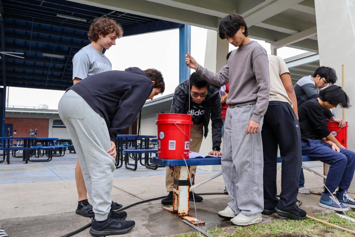 Juniors Hryday Patel, Joshua Mika, Andy Guam, and sophomore Kirin Reiter collect data for their AP Physics lab on Jan. 15, 2025. "This lab we call 'five gallons of energy,' physics teacher Joseph Estevez said. "It combines kinetics and dynamics, making a perfect new stuff combined with old stuff lab."