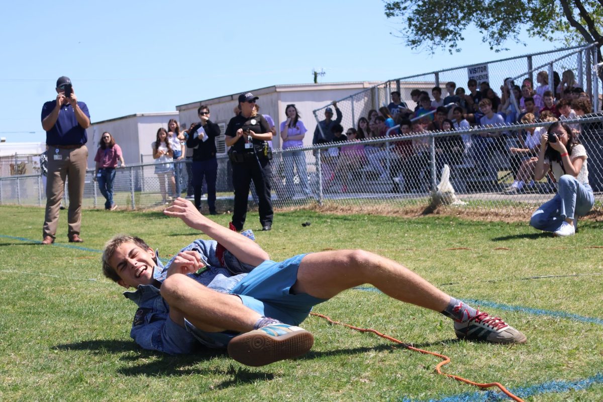 Senior Devin Haave spins on the ground while playing an air guitar.