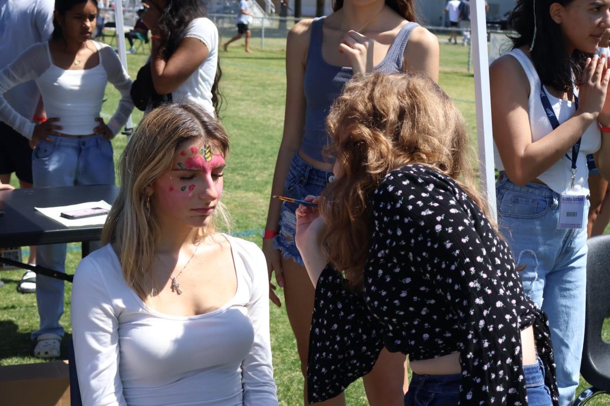 Eighth grader Isabella Quattrone gets her face painted at the theater table. “I got flowers painted on my face by Mike, who’s a tech kid for theater,” freshman Tiffany Duong said. “He was actually very professional. The experience was definitely worth the 50 cents I paid for it.”