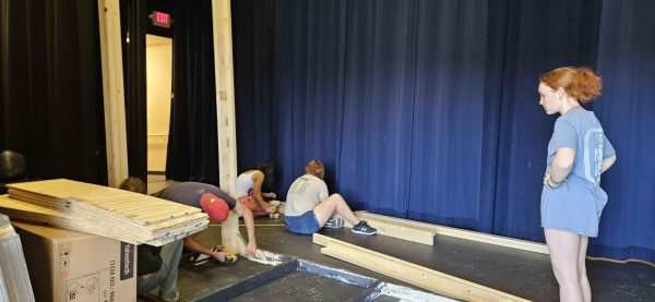 Sophomore and stage manager Genevieve Giguere (right) supervises the theater tech crew as parent volunteer Ryan Torvik (red hat) helps with building a catwalk for the "Anything Goes" set on Feb. 28.