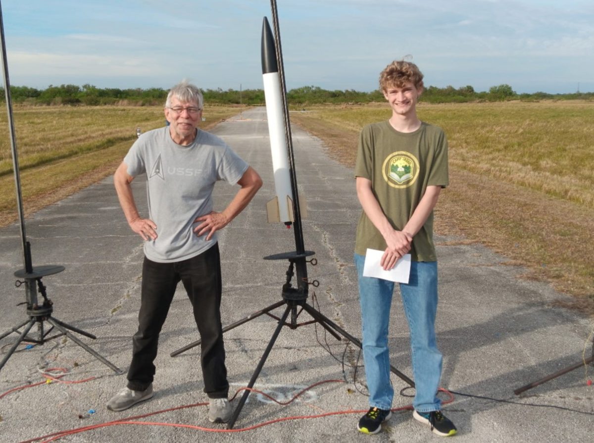 Senior Allen Neff stands beside his model rocket at the launch site, joined by his mentor, Gary Dahlke.