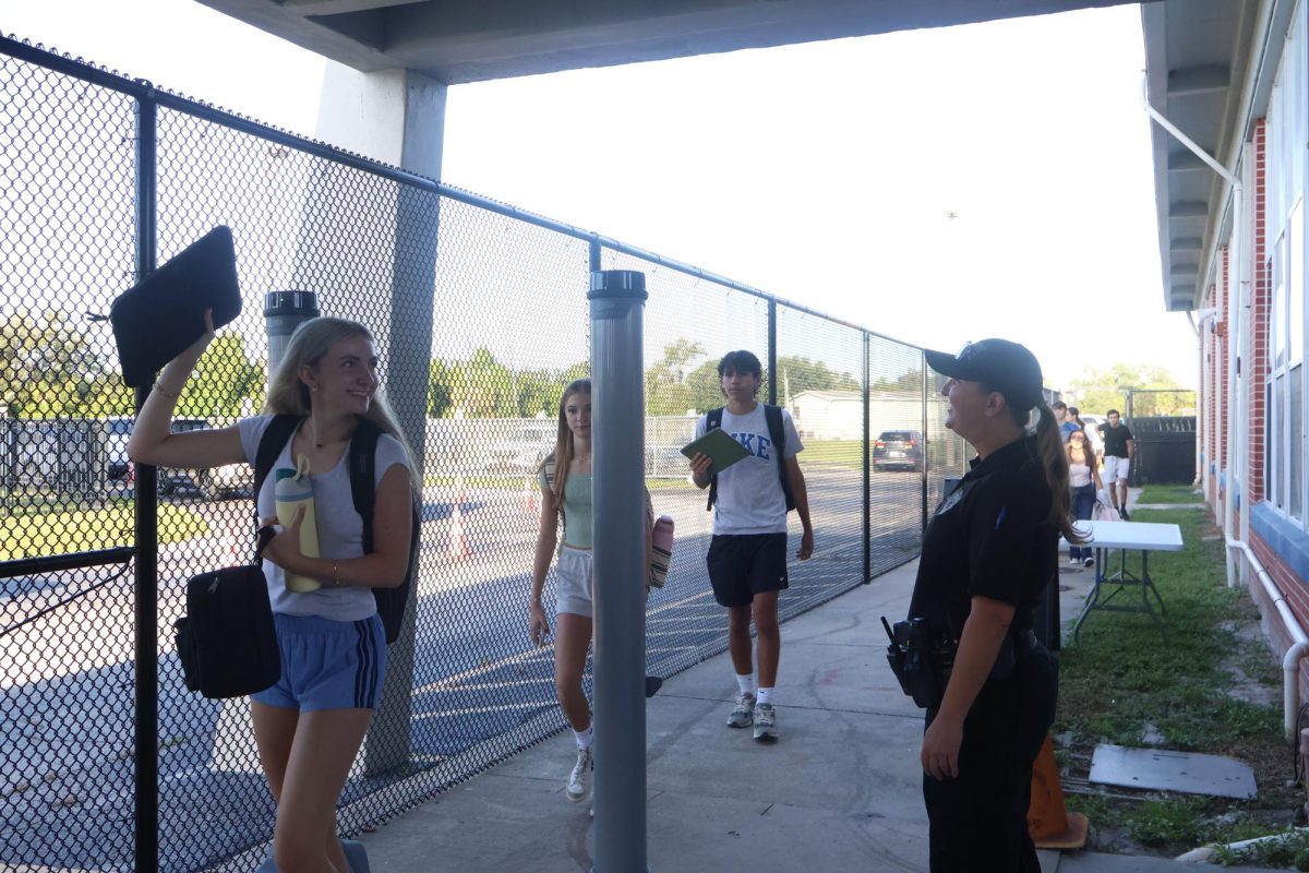 Sophomore Isabelle Gaudry walks through the metal detector, monitored by School Resource Officer Valerie Butler, on Aug. 13. “I think [the students have] been adjusting really well," Butler said. "We've had no issues, no snafus. Everything's been running smoothly, and we've been getting kids to class on time.”