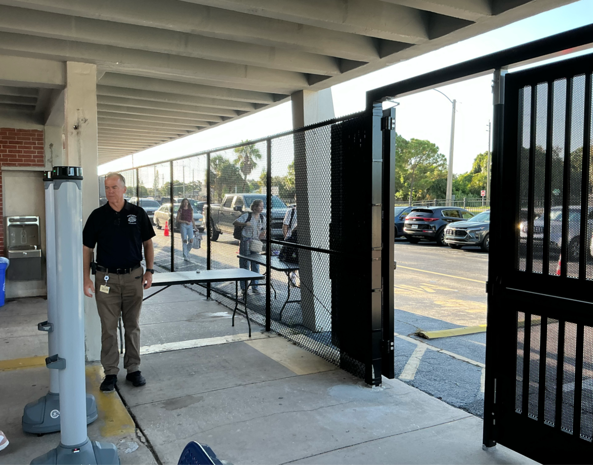 Assistant Principal Glenn Webb monitors a metal detector located next to the newly fenced high school car loop on Aug. 22. Fences and gates were added to the perimeter of the school to meet a state requirement.