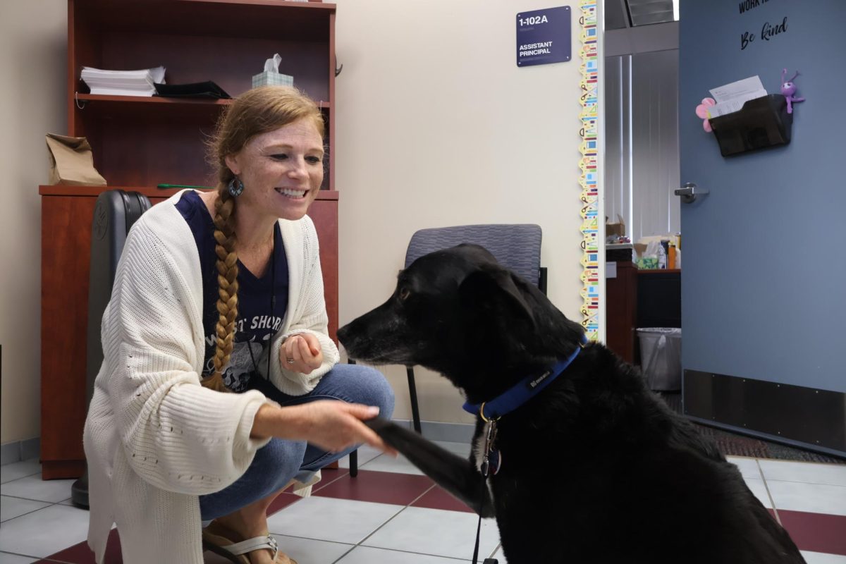 Meeting Tesla the therapy dog for the first time in Assistant Principal Sarah Perry’s office, science teacher Stefani Archibald greets her with a handshake and smile on Sept. 5.