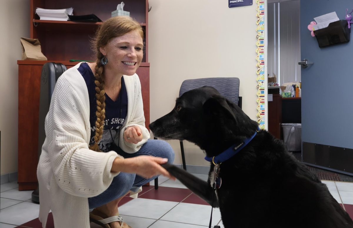 Meeting Tesla the therapy dog for the first time in Assistant Principal Sarah Perry’s office, science teacher Stefani Archibald greets her with a handshake and smile on Sept. 5.