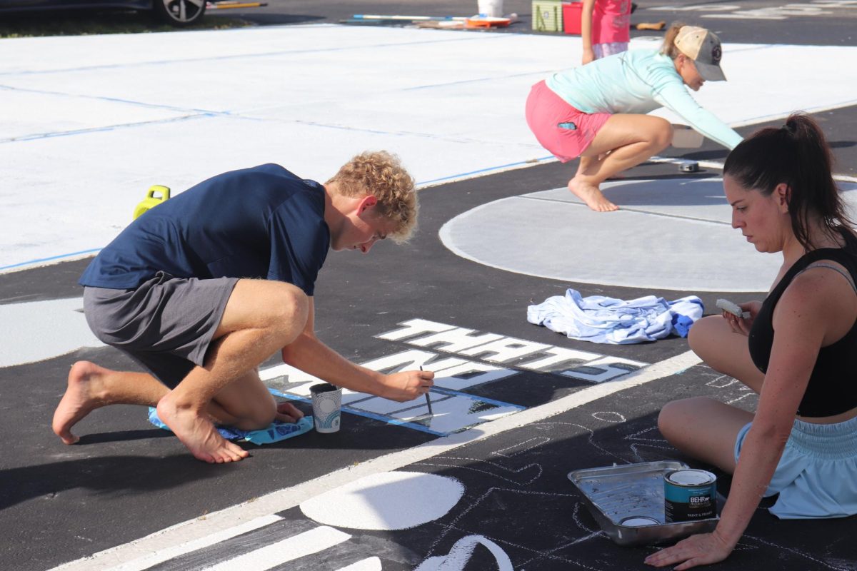 Senior Jackson Theiler (left) paints his parking spot on Sept. 7.