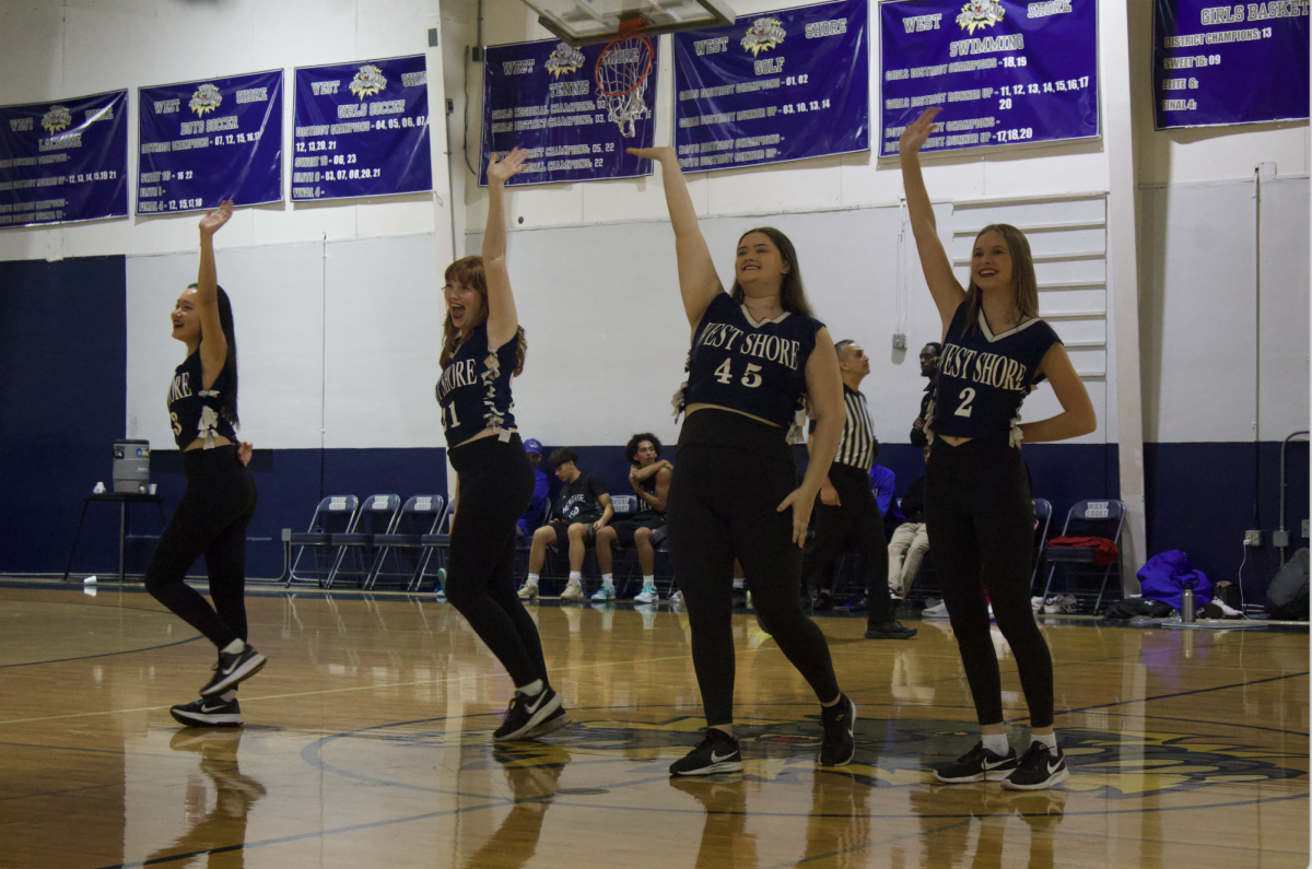 Waving at the crowd, the varsity Purrfections prepare to leave the basketball court after performing their routine called “Pump it Up,” which is named after the first song played during the dance, on Nov. 18.