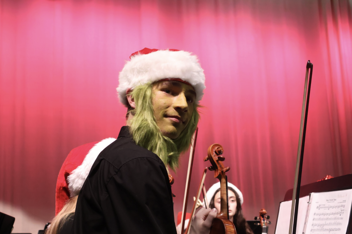 Dressed as the Grinch, freshman Josh Olson plays as first violin during the song “You're a Mean One, Mr. Grinch” during the winter concert on Dec. 5. “I really enjoyed playing and it was super fun to mess around and modify my face to dress up,” Olson said. “I figured it would be fun to try a new look.”