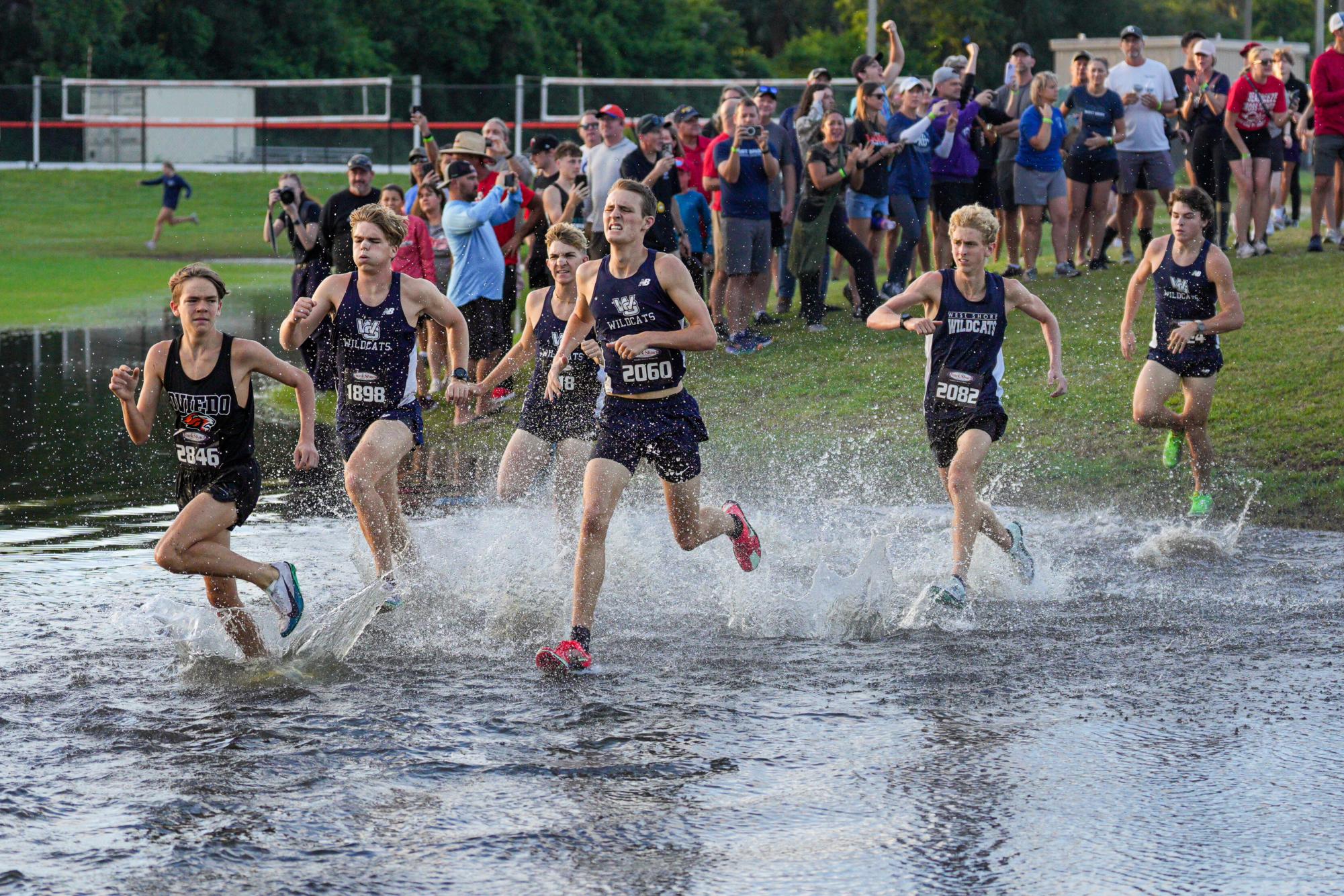 The top five varsity varsity runners charge through a pool of standing water during the first mile of the Savannah and David Mohney Memorial Invitational on Sept. 13. The team captured second place in the meet with a score of 61.