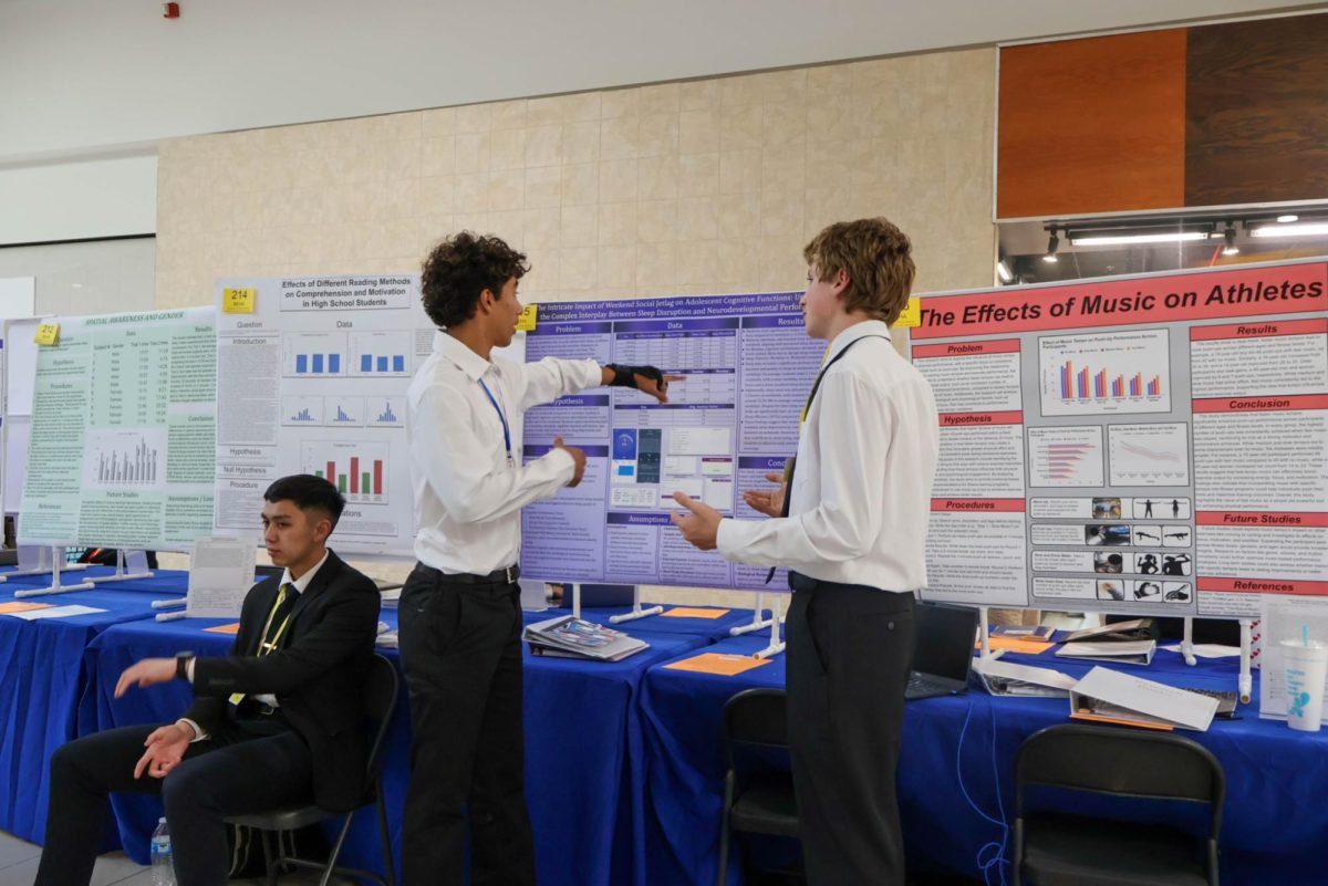Discussing his behavioral studies with sophomore Mason Zuk, alumnus Athan Zaiden presents his AP Capstone Research Project at the South Brevard Engineering and Science fair in the Melbourne Square Mall on Feb. 7.