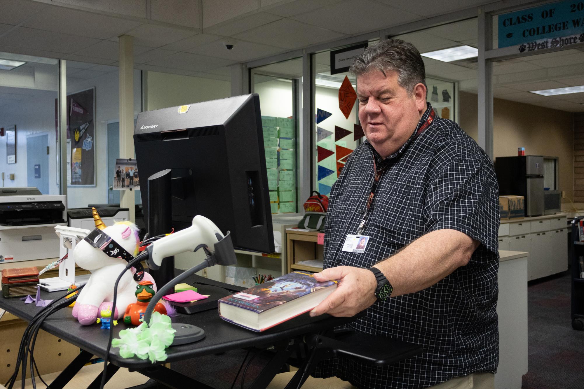 Scanning the barcode of a library book, media specialist Mike Drake checks out a book for a student in the library on Feb. 5.