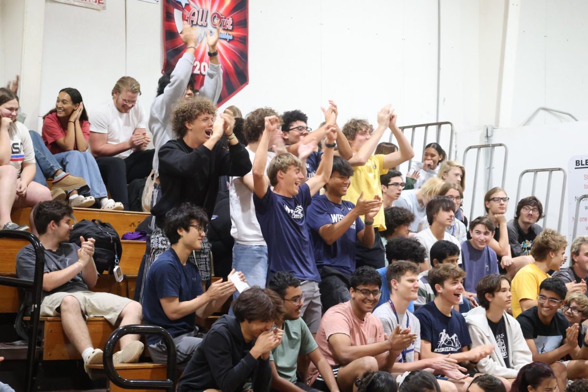 Cheering on the senior class candidates, juniors Landon Plechaty (left) and Brian Duong stand up alongside the crowd and cheer in the gym on Wednesday,  April 22.