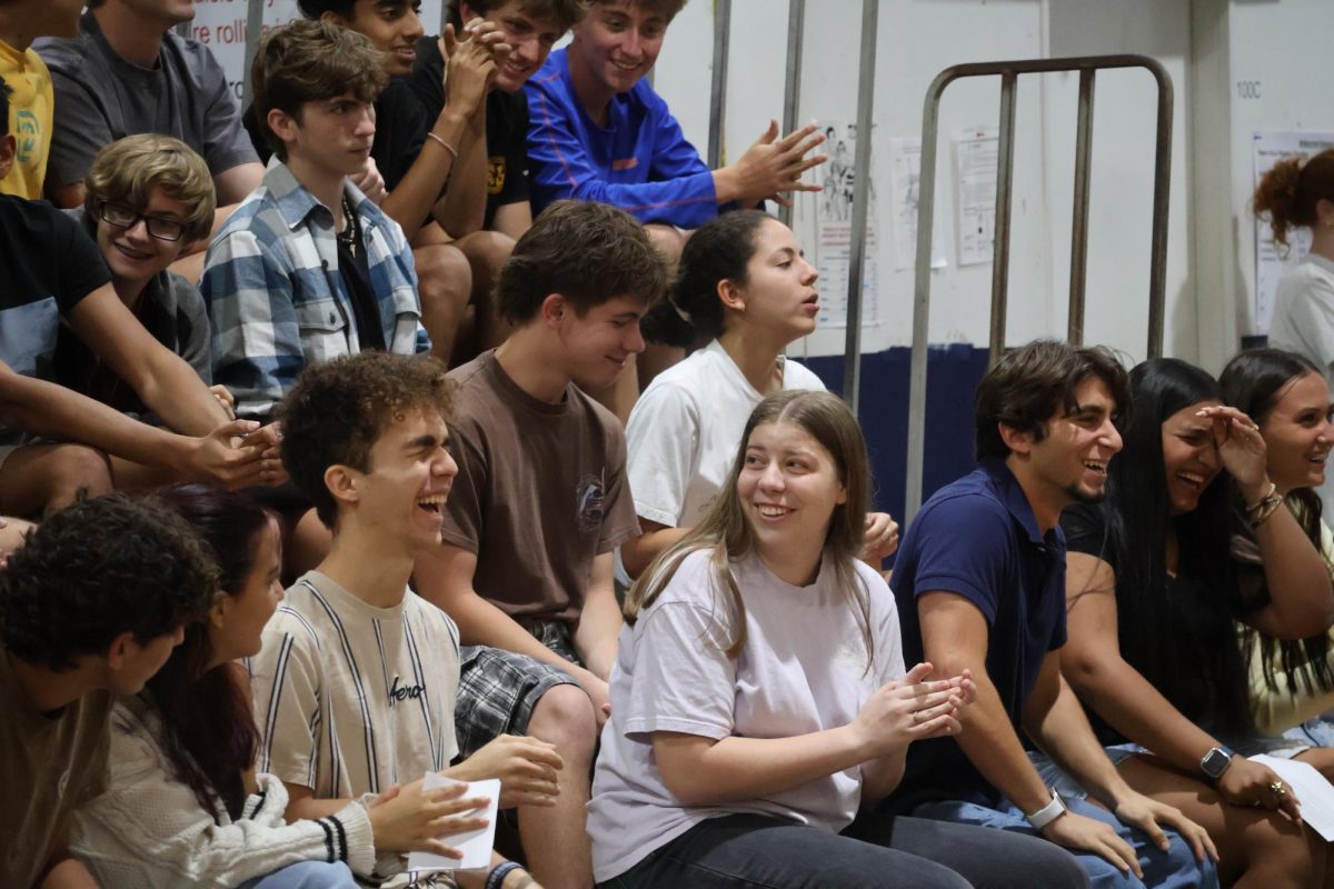 Reacting to the senior class speeches, juniors David Amador (left) and Sophie Ann Miles applaud in the gym on Wednesday, April 22. 