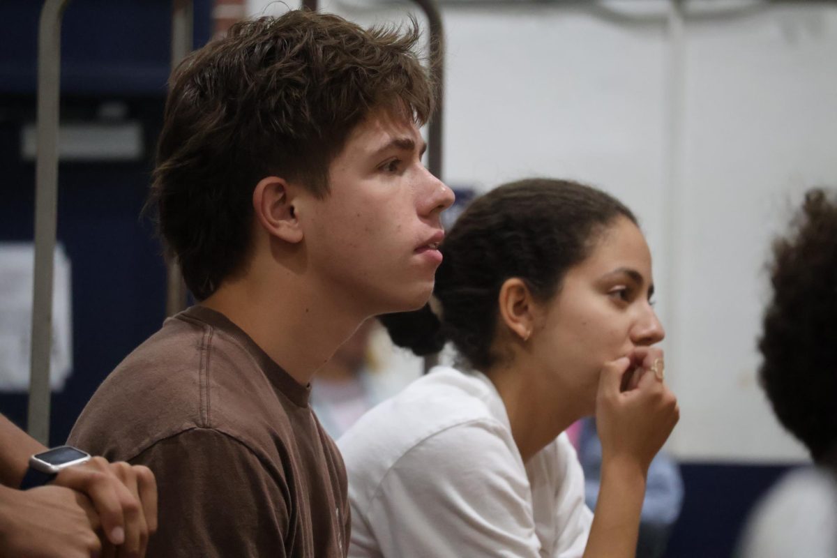 Listening to the senior candidate speeches, juniors Gabriel Worm (left) and Sofia Menendez Mendez watch from the bleachers in the gym on Wednesday, April 22. 