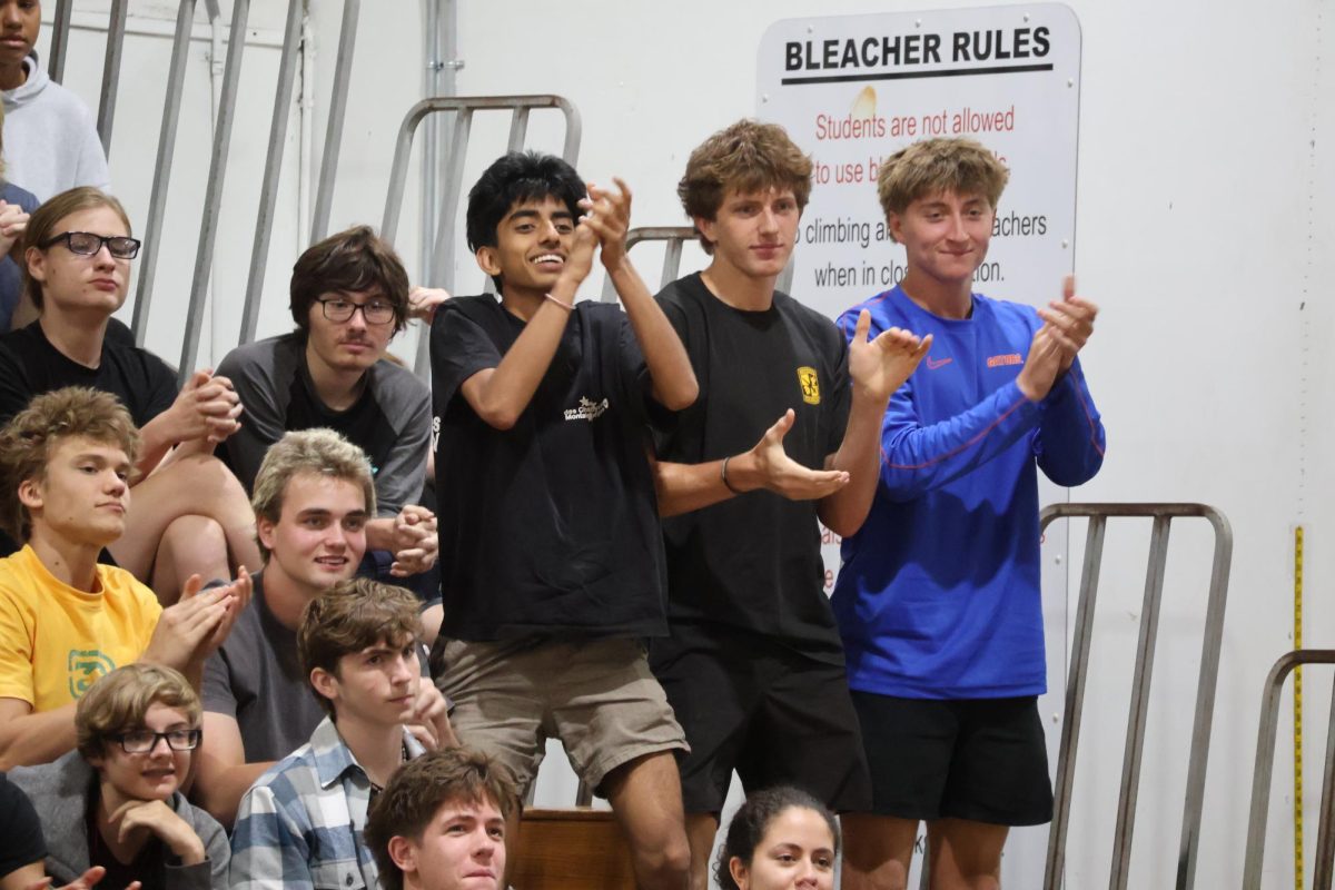 Clapping for the candidates, juniors Kush Patel (left), Austin Stovall and Maddon Villanueva stand and applaud in the gym on Wednesday, April 22. 